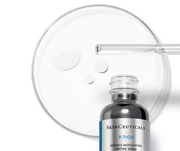 Ein Serumflaschchen von SkinCeuticals mit einer Pipette und Tropfen auf einer Petrischale.