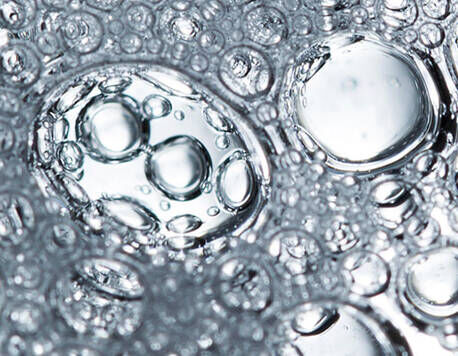 Close-up of clear water bubbles, varying in size, floating in a liquid surface, creating a textured and reflective pattern.