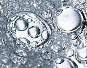 Close-up of clear water bubbles, varying in size, floating in a liquid surface, creating a textured and reflective pattern.