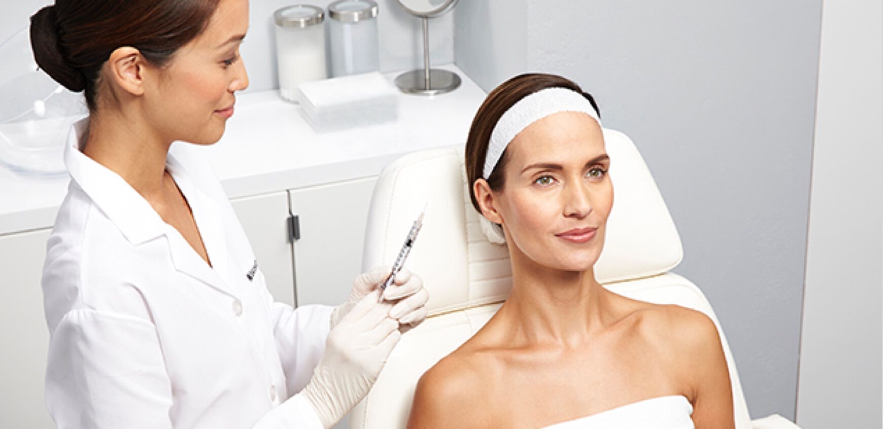 Eine Frau erhalt eine Gesichtsbehandlung in einer modernen Klinik von einer kosmetischen Fachkraft.