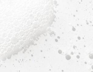 Close-up of white bubbles on a light background, creating a textured, frothy appearance.