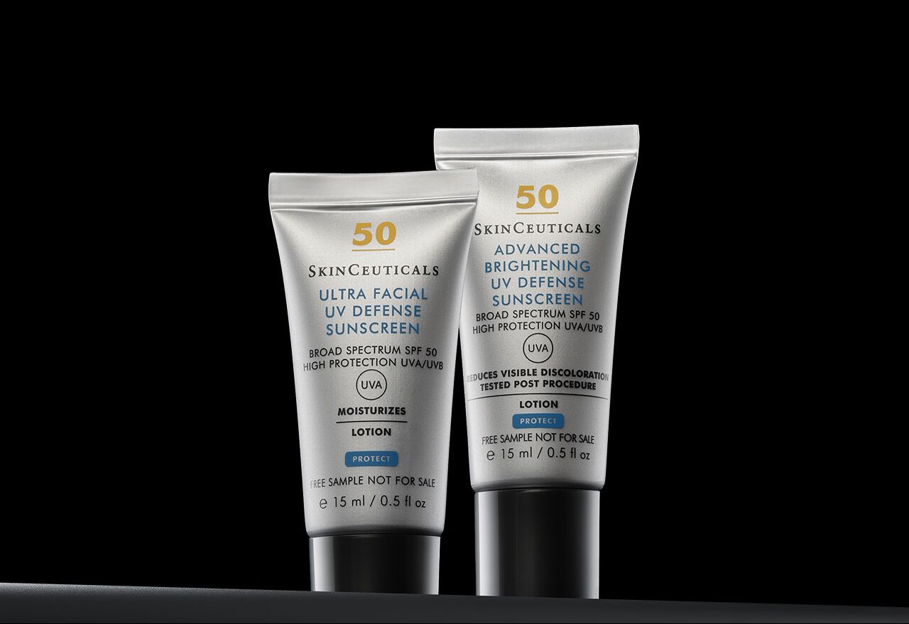 Nahaufnahme von zwei Skinceuticals-Sonnenschutzflaschen, Ultra Facial UV Defense und Advanced Brightening UV Defense, auf schwarzem Hintergrund.