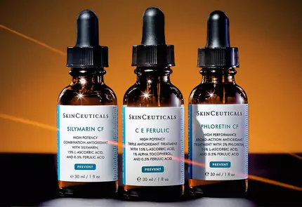 Drei Glasflaschchen mit Pipetten, die verschiedene Hautpflege-Seren von SkinCeuticals zeigen, auf einem dunklen Hintergrund.