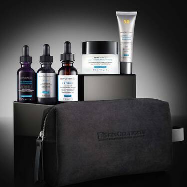 Eine Kollektion von Skinceuticals-Produkten, angeordnet auf einem schwarz-grauen, abgestuften Display vor einem dunklen Hintergrund mit Farbverlauf. Ein CE Ferulic, ein P-TIOX, ein HA Intensifier Multi-Glycan, ein A.G.E. Interrupter Advanced und ein Ultra Facial UV Defense Sunscreen. Im Vordergrund die schwarze Skinceuticals-Tasche.