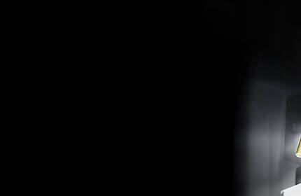 Ein Regal mit verschiedenen Hautpflege-Seren in Flaschen, die auf einem schwarzen Hintergrund stehen.