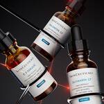 Drei Flaschchen Skincare-Seren von SkinCeuticals mit unterschiedlichen Inhaltsstoffen auf einem stilvollen Hintergrund.