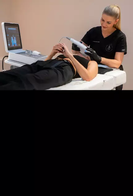 Eine Arztin behandelt das Gesicht einer liegenden Patientin mit einem medizinischen Gerat