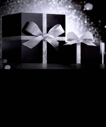 EineNahaufnahme von zwei SkinCeuticalsSerumflaschen, A.G.E Interrupter Ultra Serum und P-Tiox,die vor einer dunklen Geschenkbox mit einer funkelnden goldenen Schleife stehen.