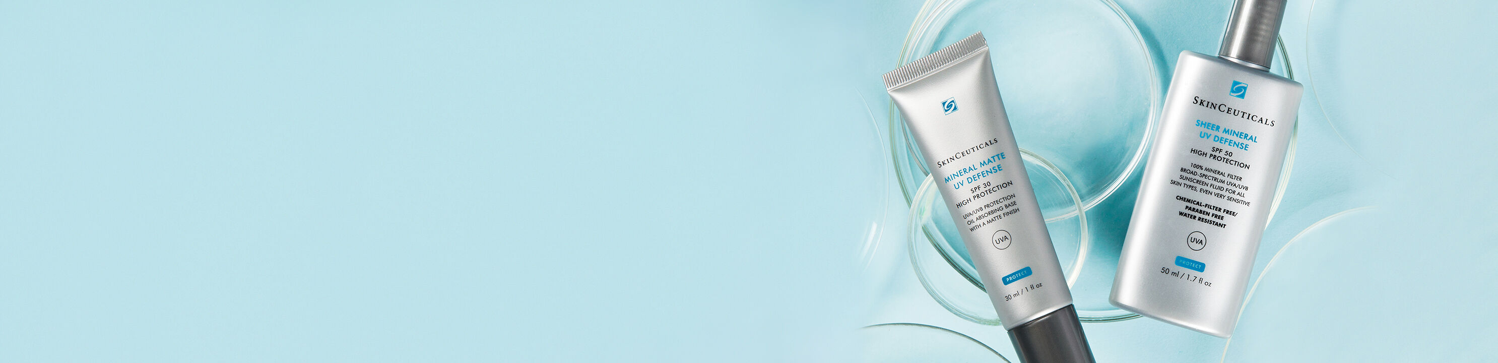 Bild von zwei Hautpflegeprodukten auf einem hellblauen Hintergrund, darunter ein Tuben- und ein Flakonprodukt.