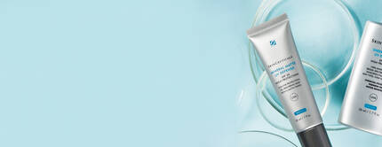 Bild von zwei Hautpflegeprodukten auf einem hellblauen Hintergrund, darunter ein Tuben- und ein Flakonprodukt.
