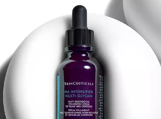 Ein Flaschchen mit Hautpflege-Serum von SkinCeuticals, das auf einem weißen, geschwungenen Hintergrund steht.
