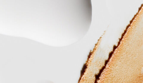 Abstract image featuring a smooth, white surface with a golden-brown textural detail on one edge, suggesting a blend of minimalism and elegance.