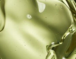 Nahaufnahme von grunem Ol mit sanften Wellen und Blasen, die Licht reflexieren.