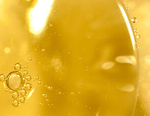 Nahaufnahme von Blasen in goldenem Ol, das Licht reflektiert und eine lebendige, flussige Textur zeigt.