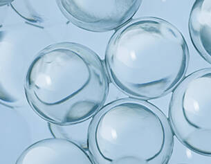 Durchsichtige, kugelformige Blasen auf blauen Hintergrund, die Licht reflektieren und fur einen transparenten Effekt sorgen.