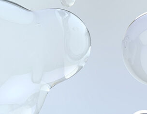 Transparente, flussige Tropfen auf grauem Hintergrund, die eine sanfte, organische Form erzeugen.