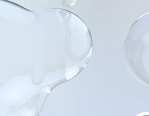 Transparente, flussige Tropfen auf grauem Hintergrund, die eine sanfte, organische Form erzeugen.