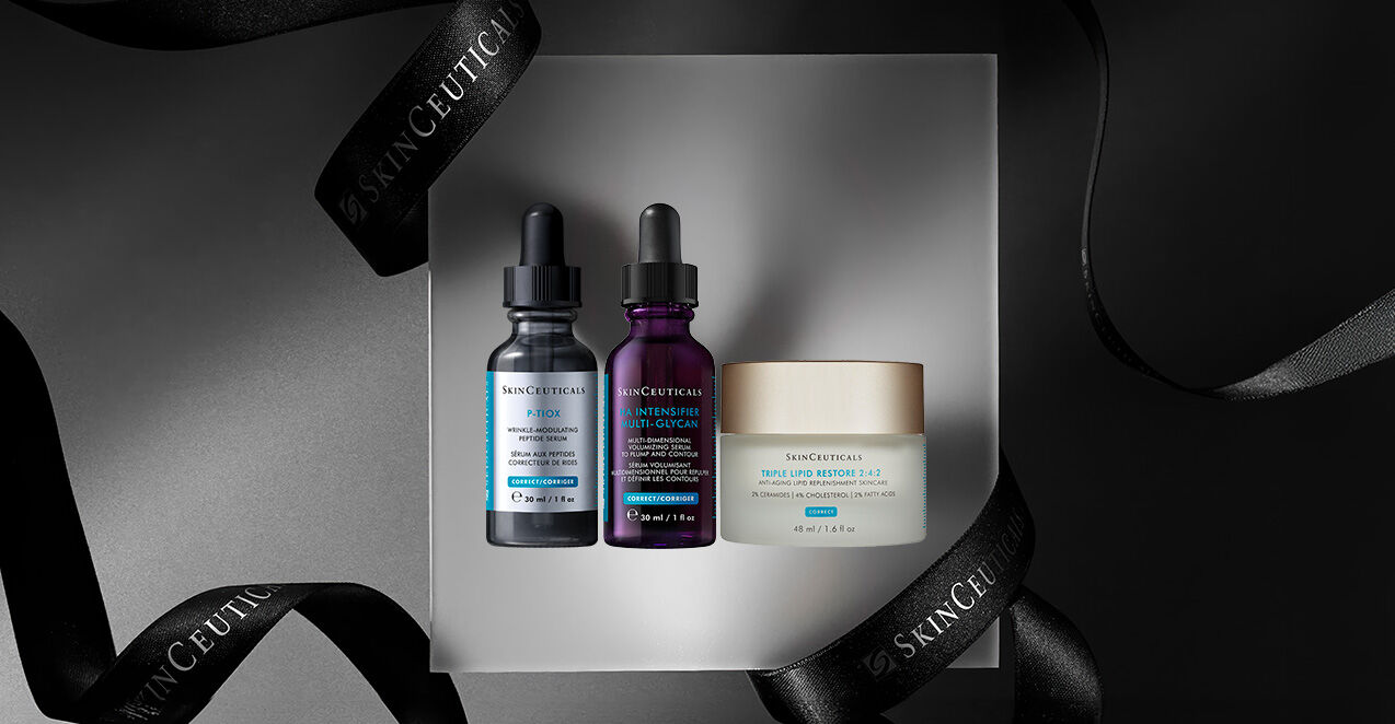 Three skincare products presented on a light gray platform, surrounded by a black ribbon with "SKINCEUTICALS" printed on it. The products include two dropper bottles and a cream jar.