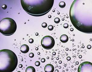 A cluster of iridescent bubbles of varying sizes against a purple background, showcasing light reflections and reflections.