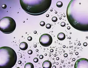 A cluster of iridescent bubbles of varying sizes against a purple background, showcasing light reflections and reflections.