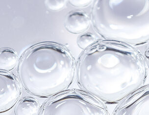 Nahaufnahme von klaren Wassertropfen, die auf einer reflektierenden Oberflache schweben.