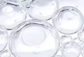 Klares Wasser mit mehreren Luftblasen in unterschiedlicher Große vor hellem Hintergrund.