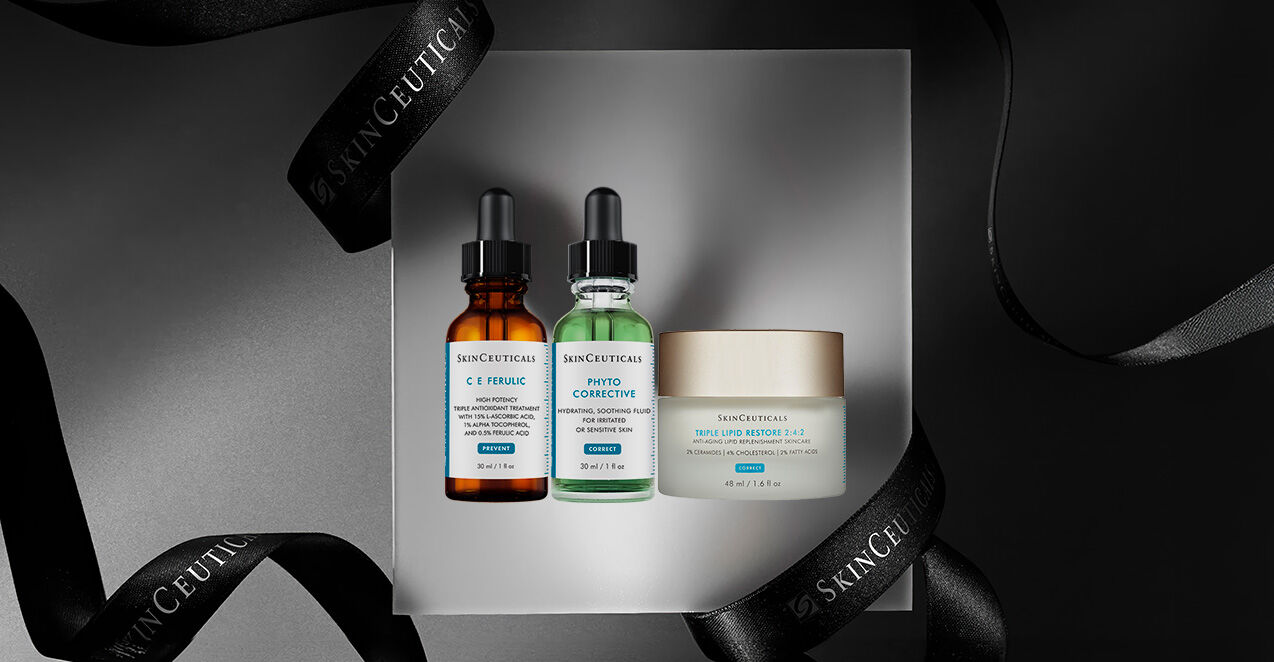 A flat lay of three skincare products from SkinCeuticals, including two serum bottles and a cream jar, presented on a box with decorative black ribbons.