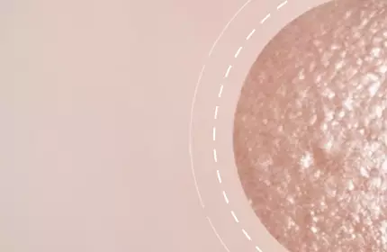 A close-up of a smooth, textured surface in a peachy tone, with a circular inset highlighting the texture details. The background is a soft, blurred gradient.