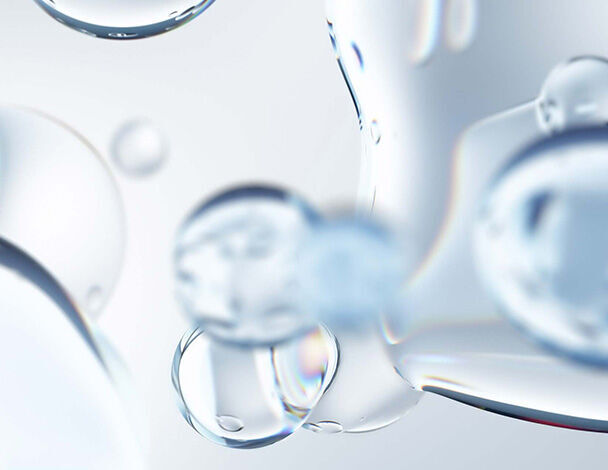 Detailaufnahme von transparenten Wassertropfen auf einem hellen Hintergrund, die Licht reflektieren und glitzern.