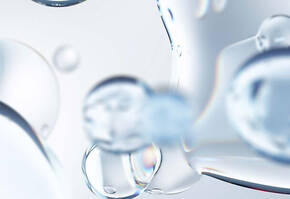 Detailaufnahme von transparenten Wassertropfen auf einem hellen Hintergrund, die Licht reflektieren und glitzern.