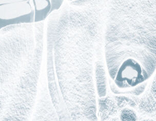 Close-up of a textured surface with soft, abstract shapes in shades of white and light gray, resembling ice or frost.