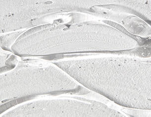 Close-up of clear, gel-like substance with smooth, flowing textures on a light background.