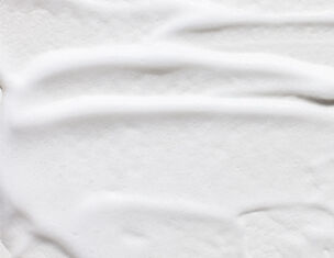 Cremeartige Textur auf weißem Hintergrund, sanft streichend und glatt.