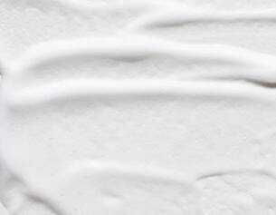 Cremeartige Textur auf weißem Hintergrund, sanft streichend und glatt.