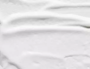 Cremeartige Textur auf weißem Hintergrund, sanft streichend und glatt.