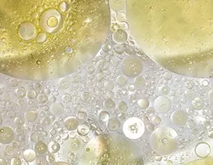 Nahaufnahme von kreisformigen Blasen in transparentem, gelblichem Flussigkeitsmix, die schimmernd und lebhaft wirken.