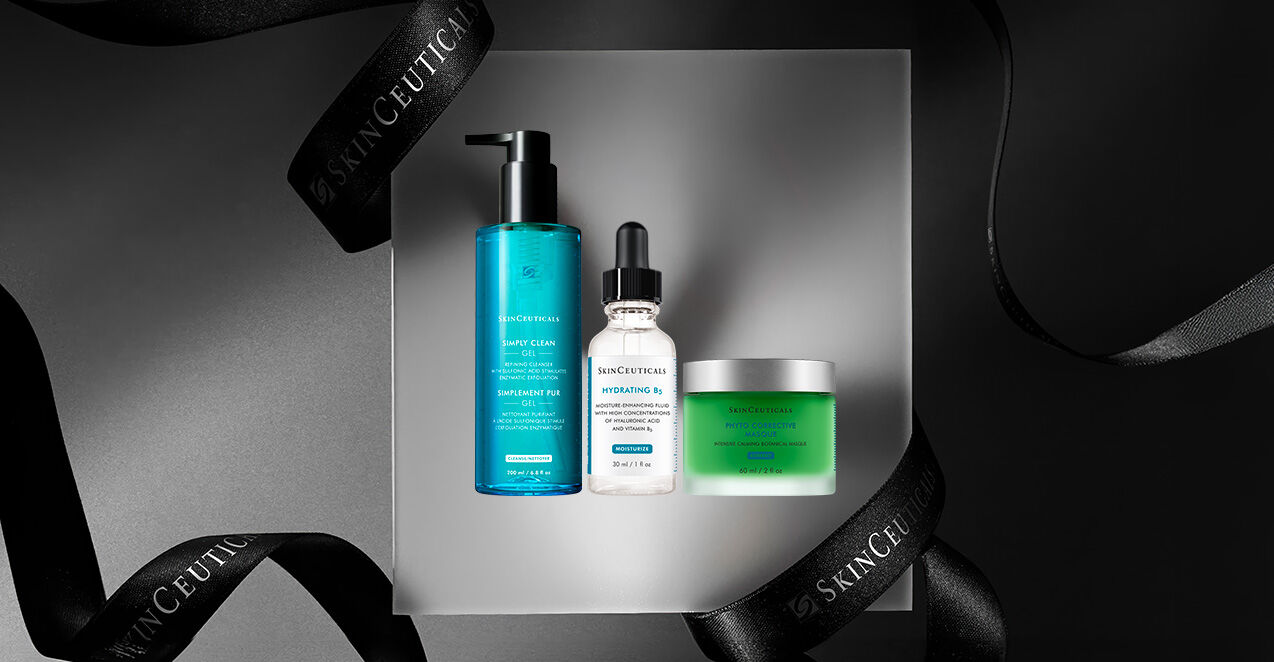 A collection of skincare products displayed on a gray surface, featuring a blue cleanser, a dropper bottle of hydrating serum, and a green cream, all surrounded by elegant black ribbons with "SkinCeuticals" branding.