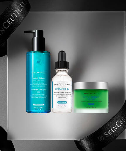 A collection of skincare products displayed on a gray surface, featuring a blue cleanser, a dropper bottle of hydrating serum, and a green cream, all surrounded by elegant black ribbons with "SkinCeuticals" branding.