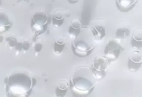 Wassertropfen und Blasen auf einer glatten, transparenten Oberflache, die das Licht reflektieren.