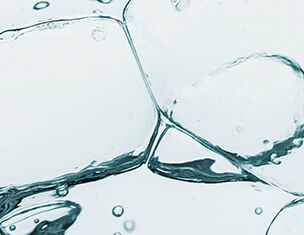 Wassertropfen und Blasen in einer transparenten Flussigkeit, die eine frische, klare Atmosphare vermittelt.