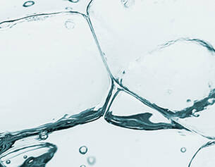 Wassertropfen und Blasen in einer transparenten Flussigkeit, die eine frische, klare Atmosphare vermittelt.