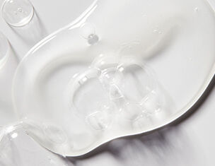Clear, viscous gel spread on a smooth surface, showcasing its glossy texture and fluid movement.