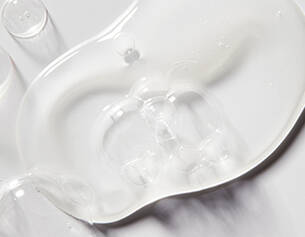 Clear, viscous gel spread on a smooth surface, showcasing its glossy texture and fluid movement.