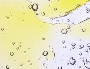 Bunte Blasen und Tropfen in gelb und transparent, die an Flussigkeiten in Bewegung erinnern.