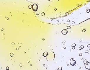 Bunte Blasen und Tropfen in gelb und transparent, die an Flussigkeiten in Bewegung erinnern.