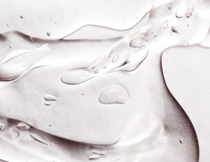 Nahaufnahme von transparentem Gel mit Wassertropfchen auf einer glatten Oberflache.