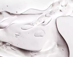 Nahaufnahme von transparentem Gel mit Wassertropfchen auf einer glatten Oberflache.